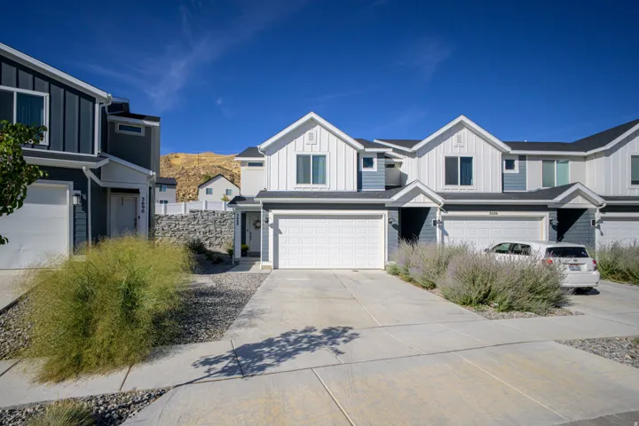 Modern townhome with attached garage, contrasting exterior siding, and a stone retaining wall