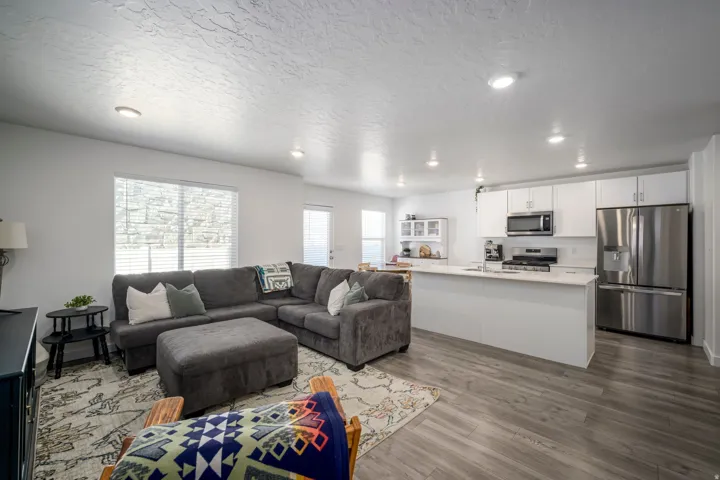 Open-concept living space featuring wood-finish flooring, recessed lighting, and a kitchen island with seating