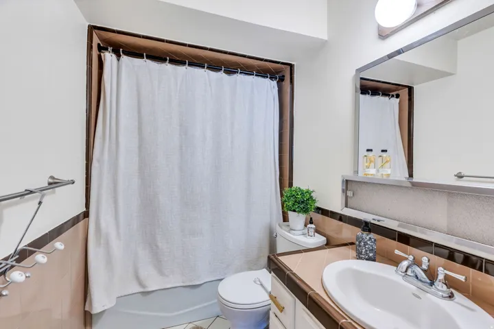 Built-in bathtub with shower, ceramic tile surround, and a vanity with an integrated sink