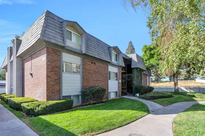 Brick exterior with dormer windows, grey shingled mansard roof, and light-colored siding accents