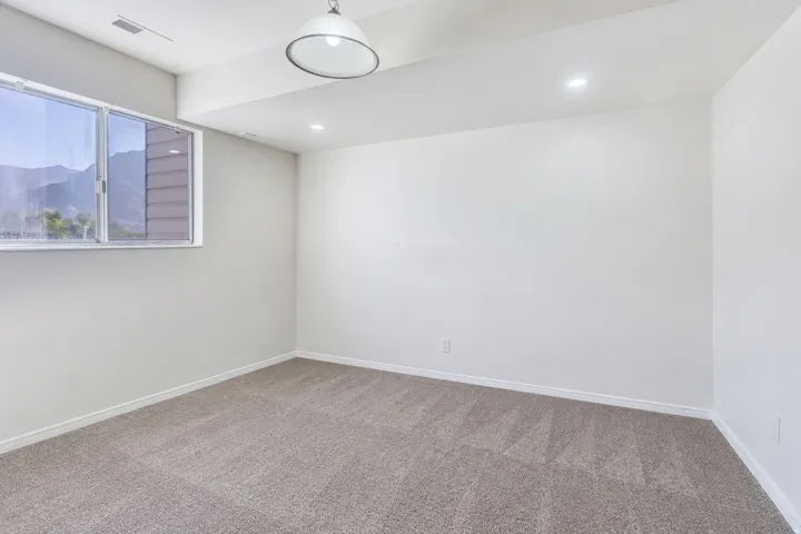 Neutral wall paint, carpet flooring, recessed lighting, window with mountain scenery, and a pendant light fixture