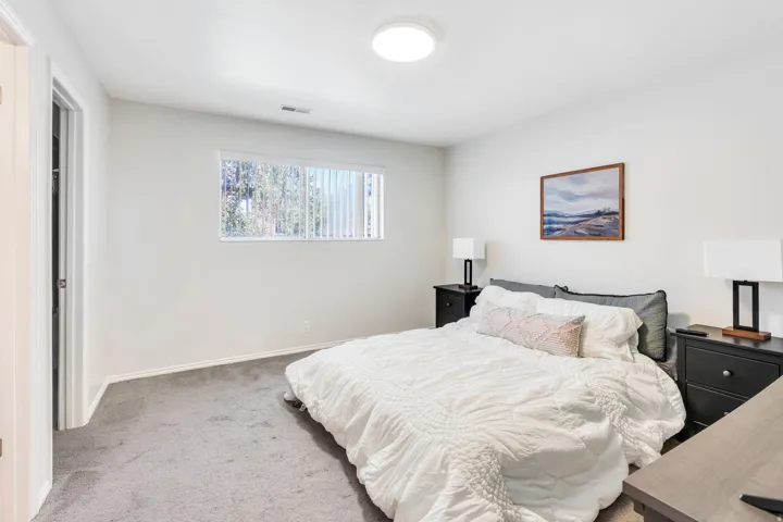 Recessed window with vertical blinds, neutral wall paint, ceiling-mounted light fixture, and gray carpeting