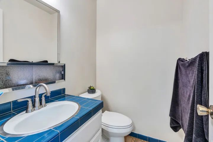 Vanity with blue tile countertop, integrated sink, and brushed nickel faucet