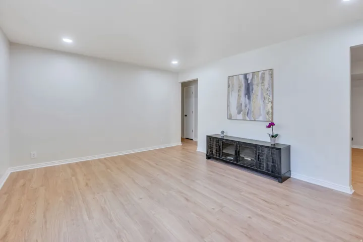 Recessed lighting, light wood-finish flooring, white walls, white trim, and a doorway