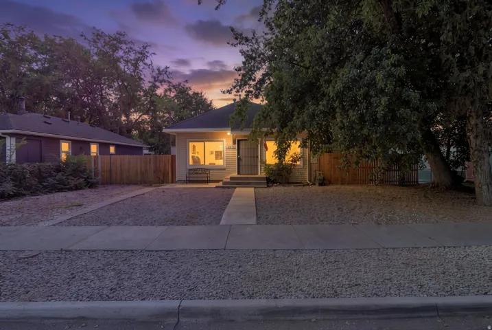 Single-story residence featuring a light-colored exterior, covered entry, and a wood privacy fence