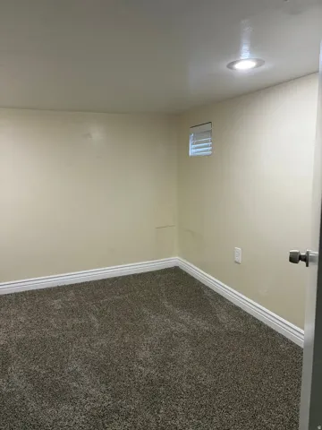 Recessed ceiling lighting, textured wall finish, and neutral tone carpet flooring