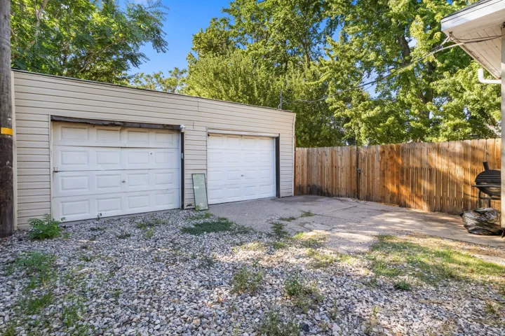 Two-car garage with horizontal siding, concrete driveway, and wood privacy fencing