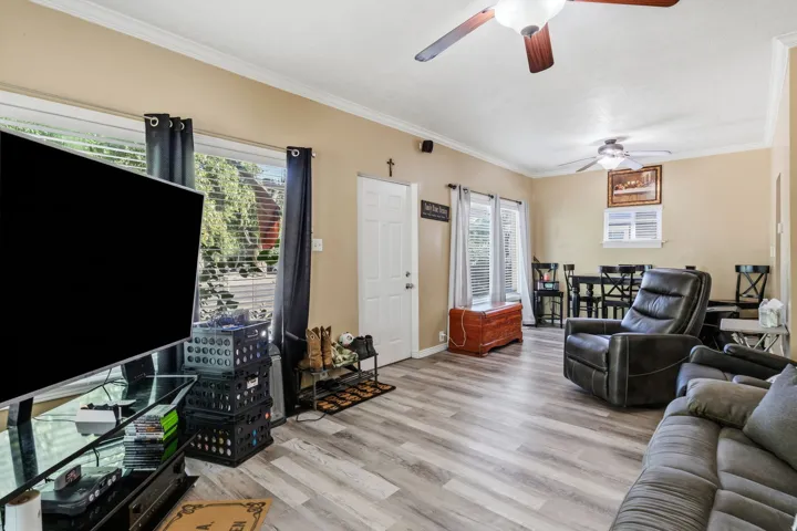 Wood-finish flooring, ceiling fans, crown molding, and multiple windows with blinds