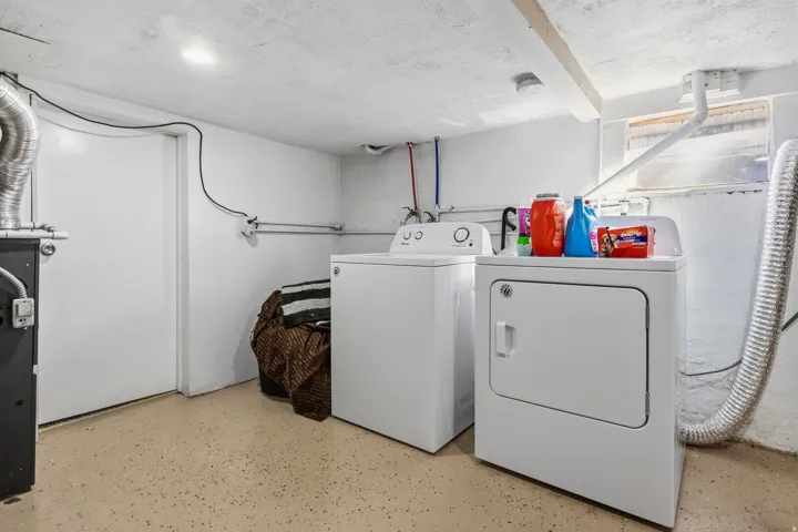 Dedicated laundry area with durable flooring and exposed ceiling beams