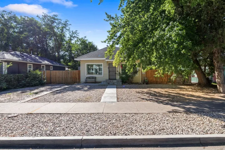 Siding exterior with a covered entry, concrete walkway, and gravel landscaping
