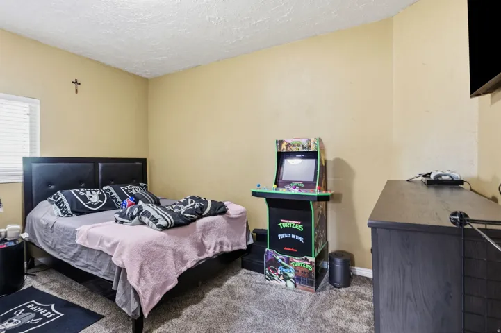 Textured ceiling, window with horizontal blinds, neutral wall paint, and gray carpet flooring