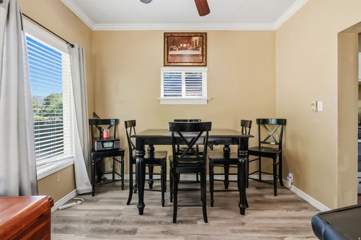 Wood-finish flooring, crown molding, and a ceiling fan