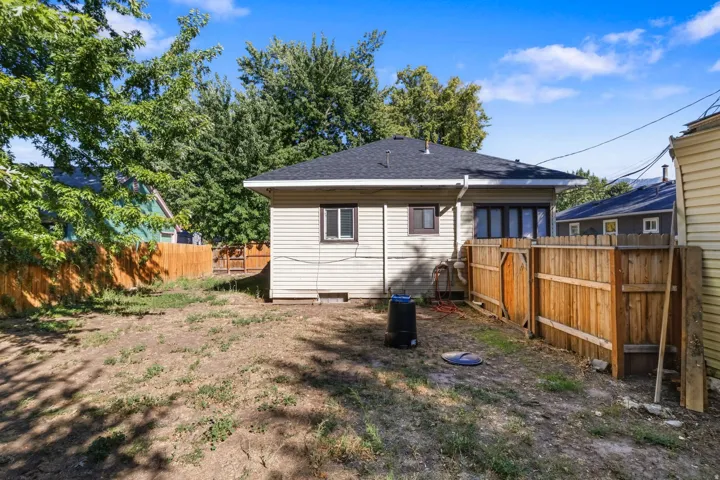 Rear exterior with horizontal siding, dark roof, and a wood fence