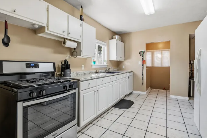 Kitchen featuring white cabinetry, light-toned countertops, a stainless steel range, and tile flooring
