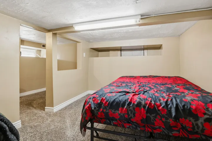 Carpeted room with recessed wall features, a dropped ceiling with fluorescent lighting, and a small window