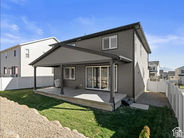Covered concrete patio with siding exterior, fenced yard, and gravel landscaping