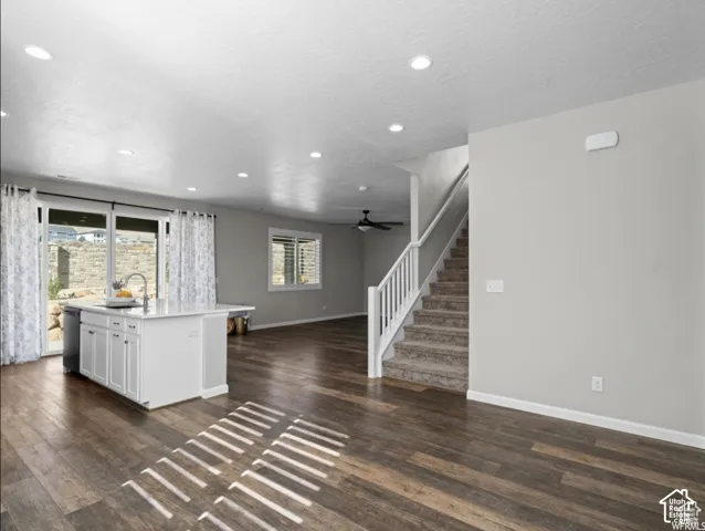 Spacious open-concept living area featuring rich wood-finish flooring, a kitchen island with built-in cabinetry, and sliding glass doors to the exterior