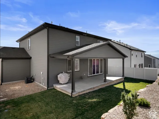 Rear exterior featuring a covered patio, sliding glass door access, and a graded lawn area