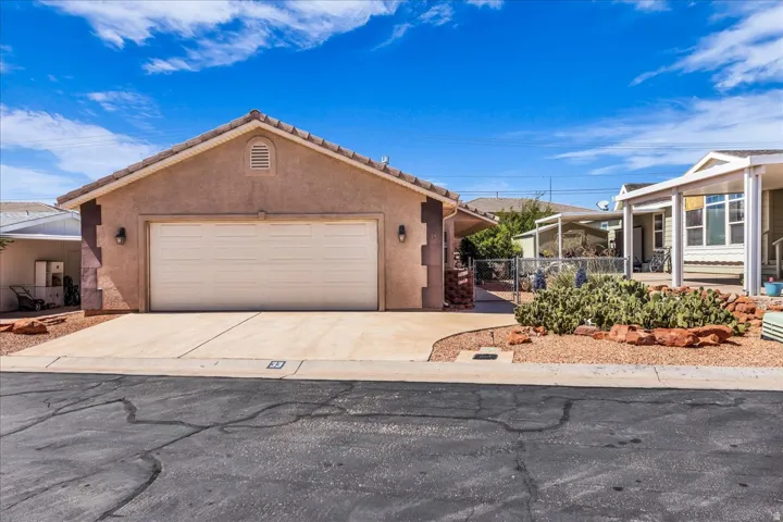 Stucco exterior with a two-car garage, concrete driveway, and desert-style landscaping