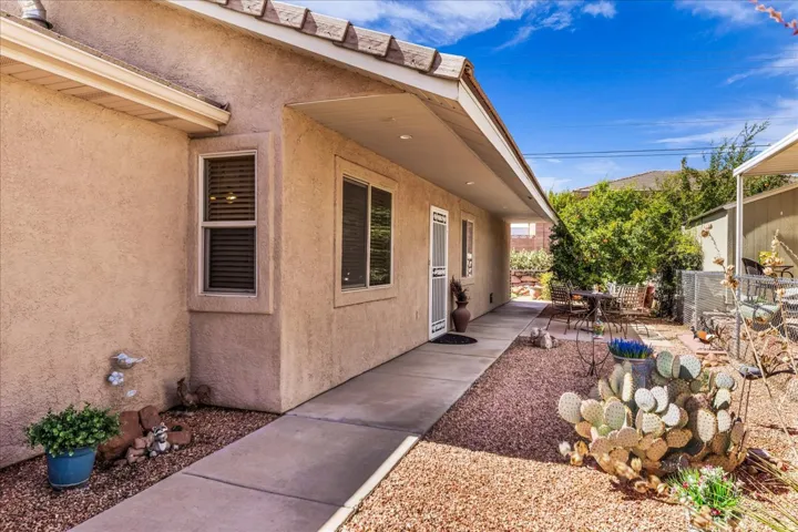 Stucco exterior with a covered walkway, decorative gravel landscaping, and established cacti