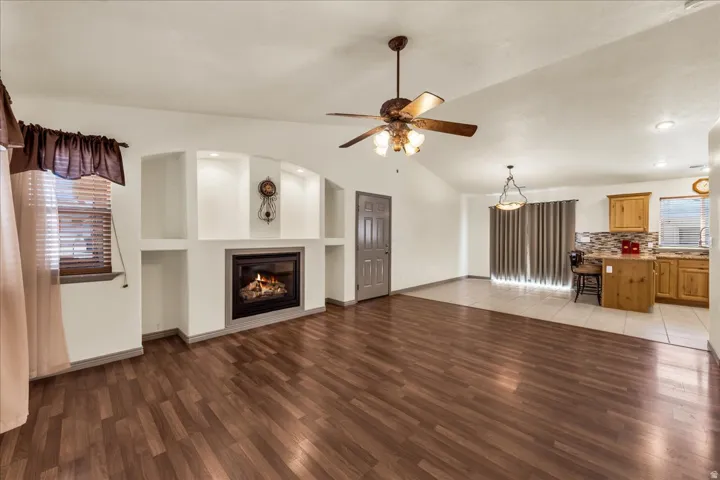 Living space featuring wood-finish flooring, a built-in fireplace with display niches, and a ceiling fan