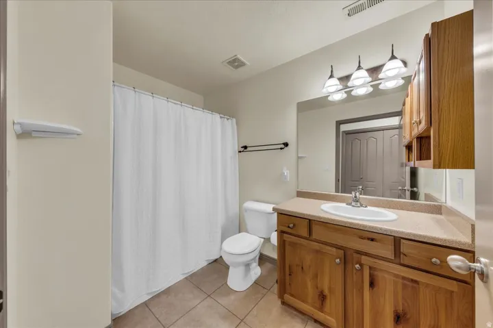 Wood-finish vanity with an integrated sink, broad mirror, and overhead tri-light fixture