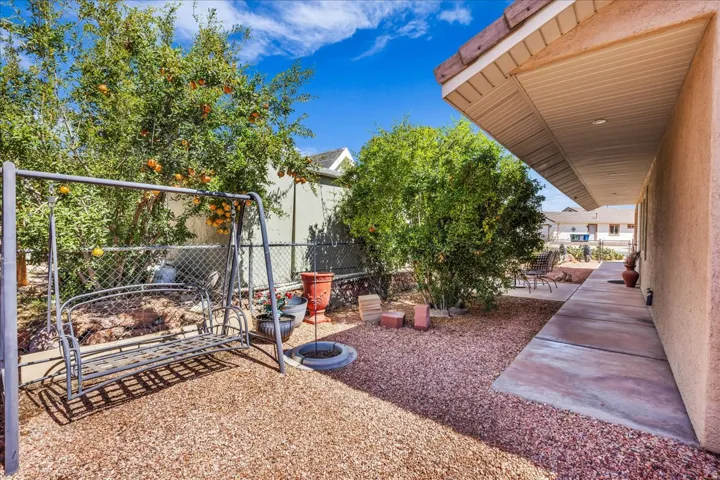 Expansive outdoor space featuring a concrete walkway, rock ground cover, and mature trees