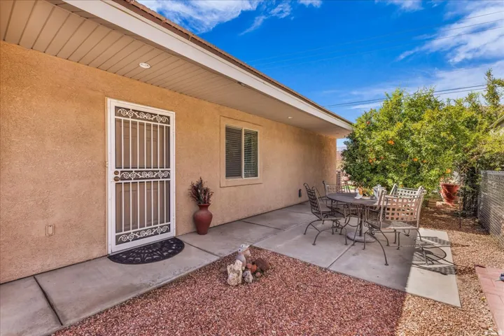 Private patio area with concrete slab, mature citrus tree, and decorative gravel landscaping