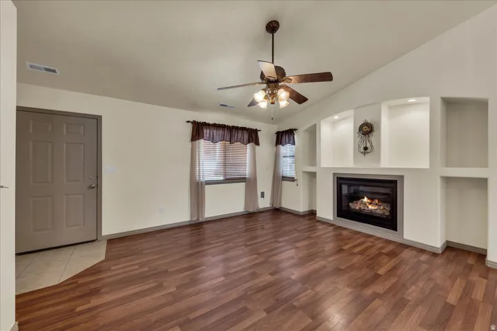 Wood-finish flooring throughout, featuring a vaulted ceiling and a ceiling fan with integrated lighting