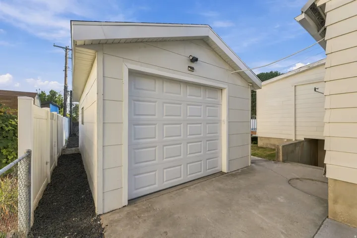 Detached garage featuring a paneled overhead door, concrete driveway, and gabled roofline with soffit detail