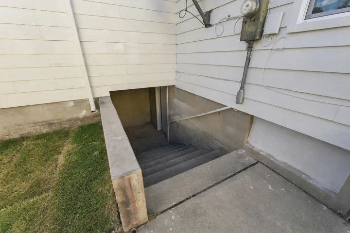 Side entrance with concrete stairs and a poured concrete foundation