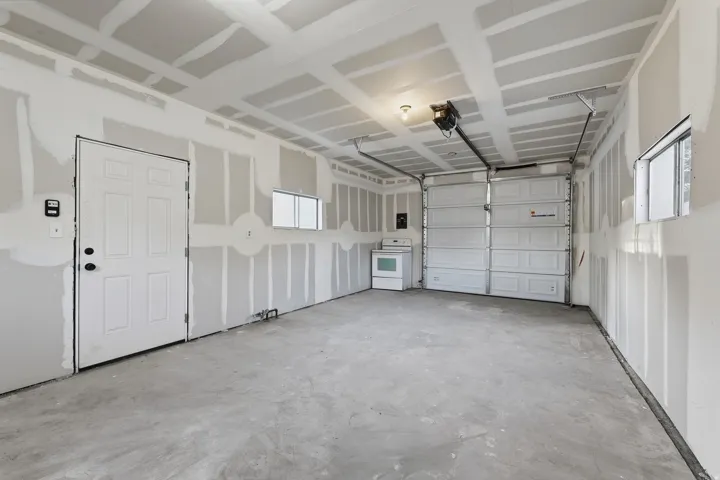 Spacious garage with exposed drywall, concrete flooring, and a paneled garage door