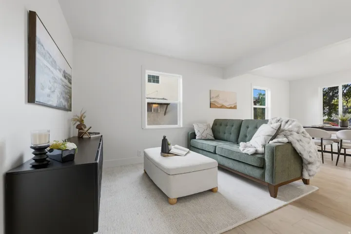 Bright living area with light wood-finish flooring, white walls, and multiple windows