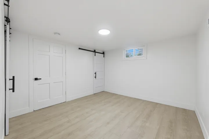 Wood-finish flooring, recessed ceiling light, white walls, white trim, and a window