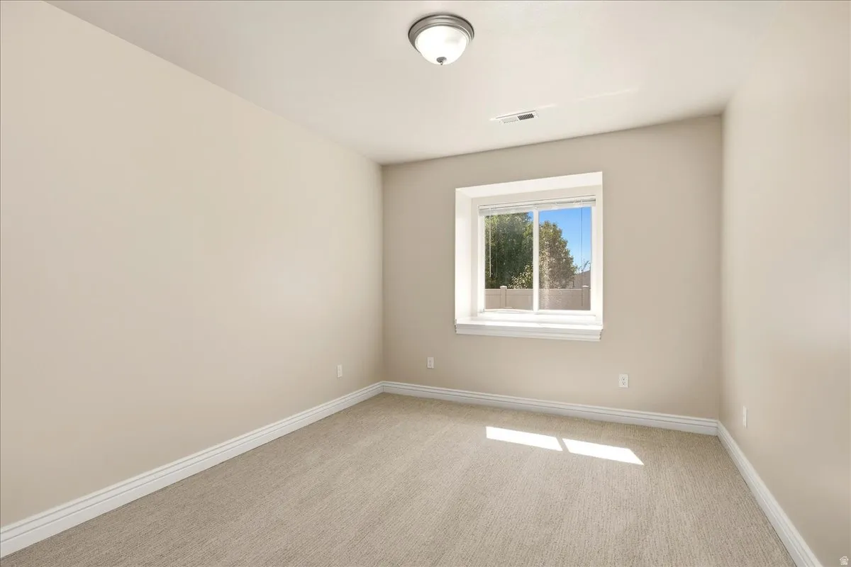 Neutral tone wall paint, carpet flooring, white trim, recessed window, and a flush mount ceiling light