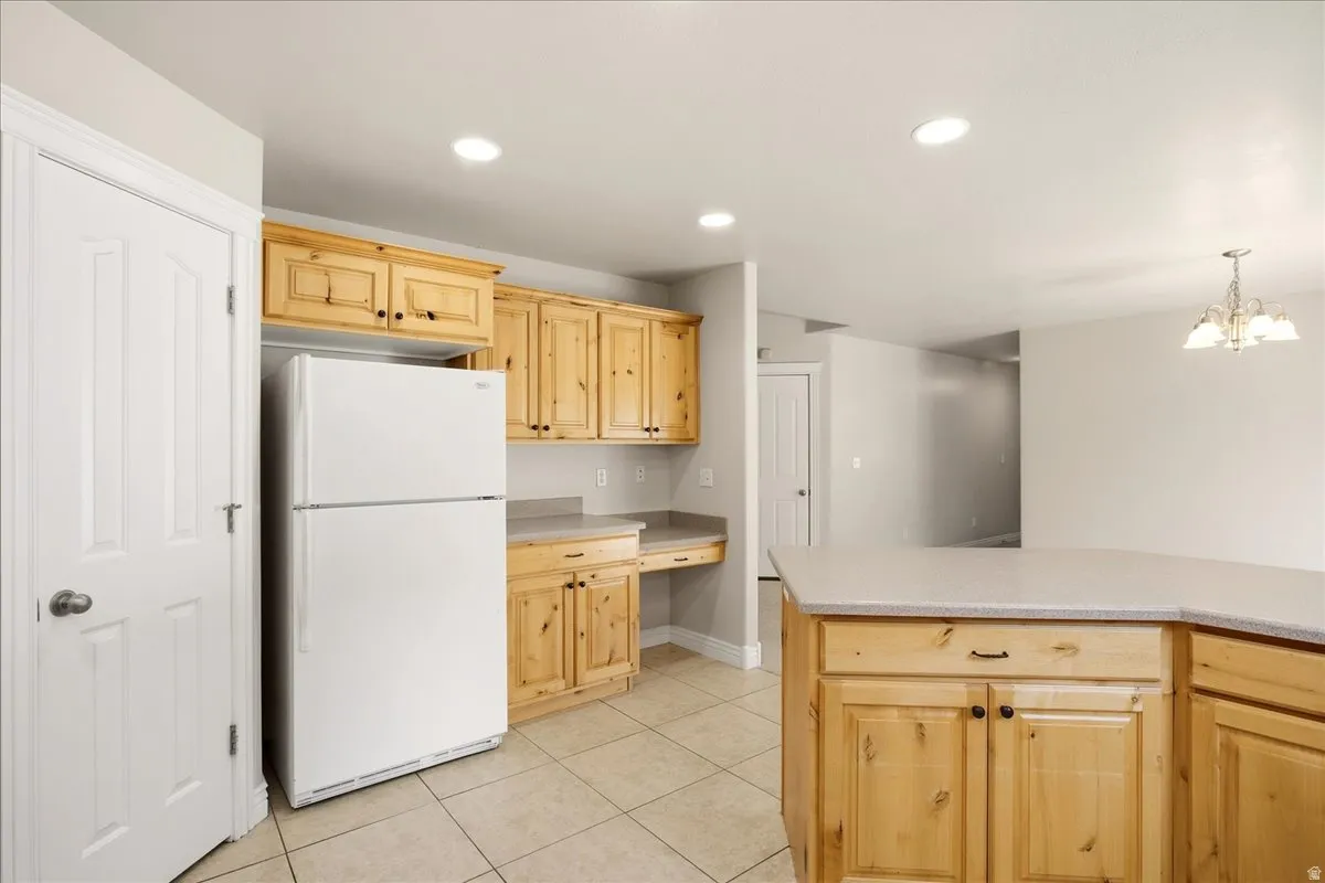 Kitchen featuring wood cabinetry, light-toned countertops, recessed lighting, and tile flooring