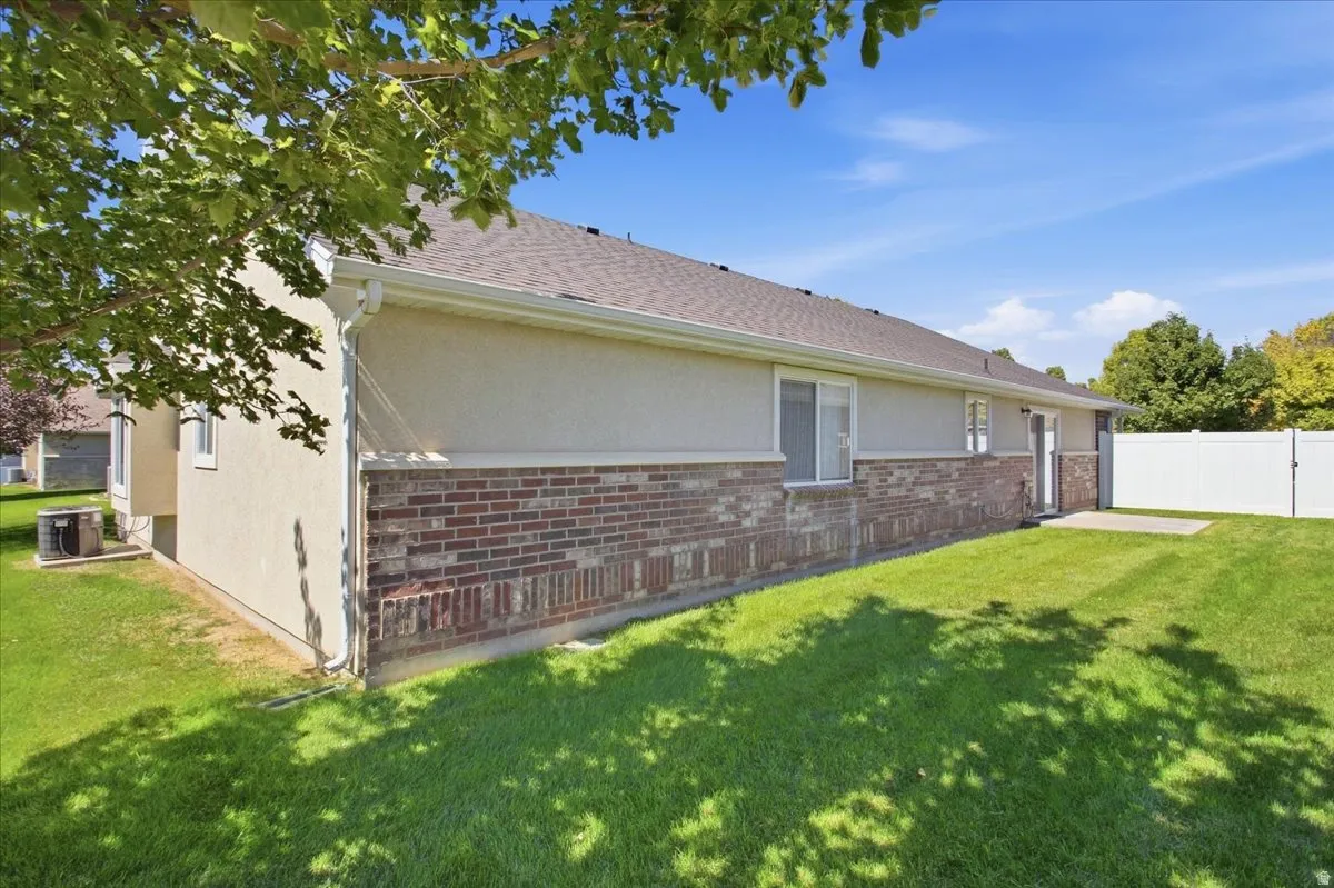 Rear exterior with a concrete patio, brick and stucco siding, white window trim, and a white privacy fence