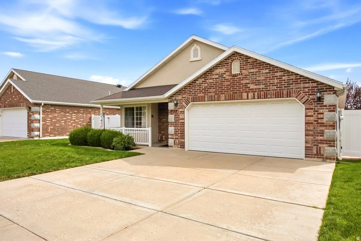Brick and stucco exterior with an attached two-car garage, concrete driveway, and covered front porch with white railing