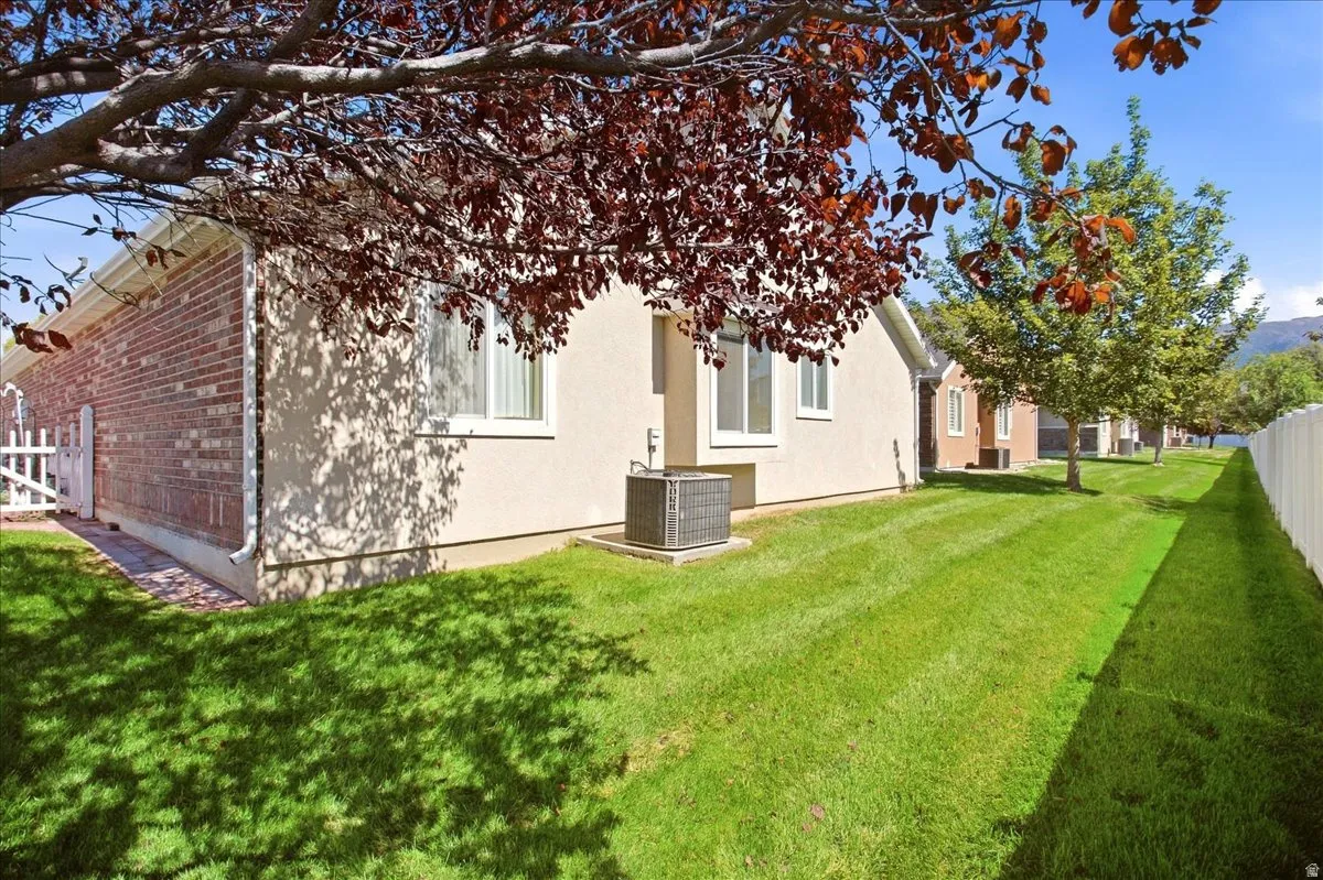 Expansive green lawn with mature trees, a white picket fence, and brick and stucco exterior finishes