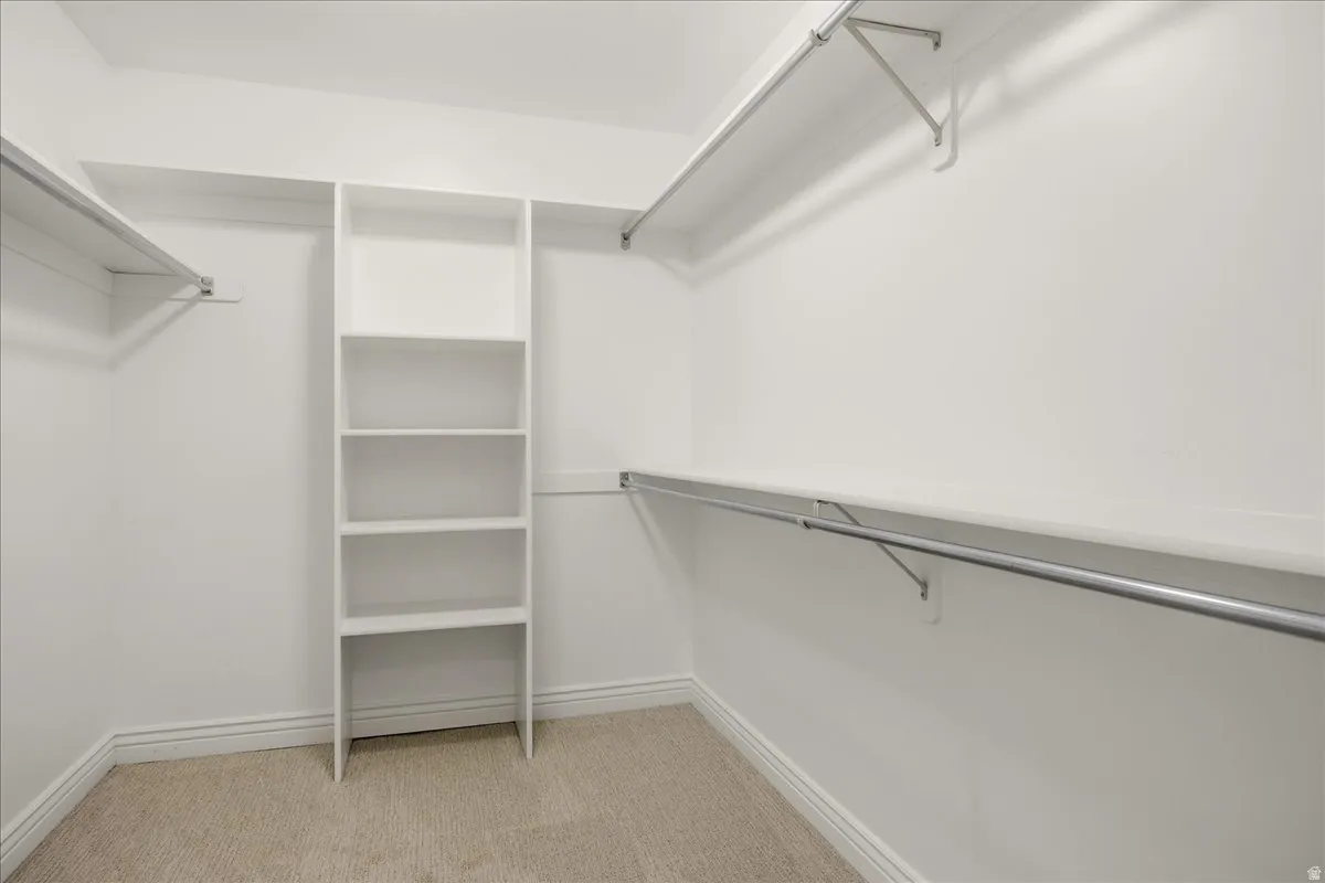 Walk-in closet with built-in shelving, multiple hanging rods, and carpeting