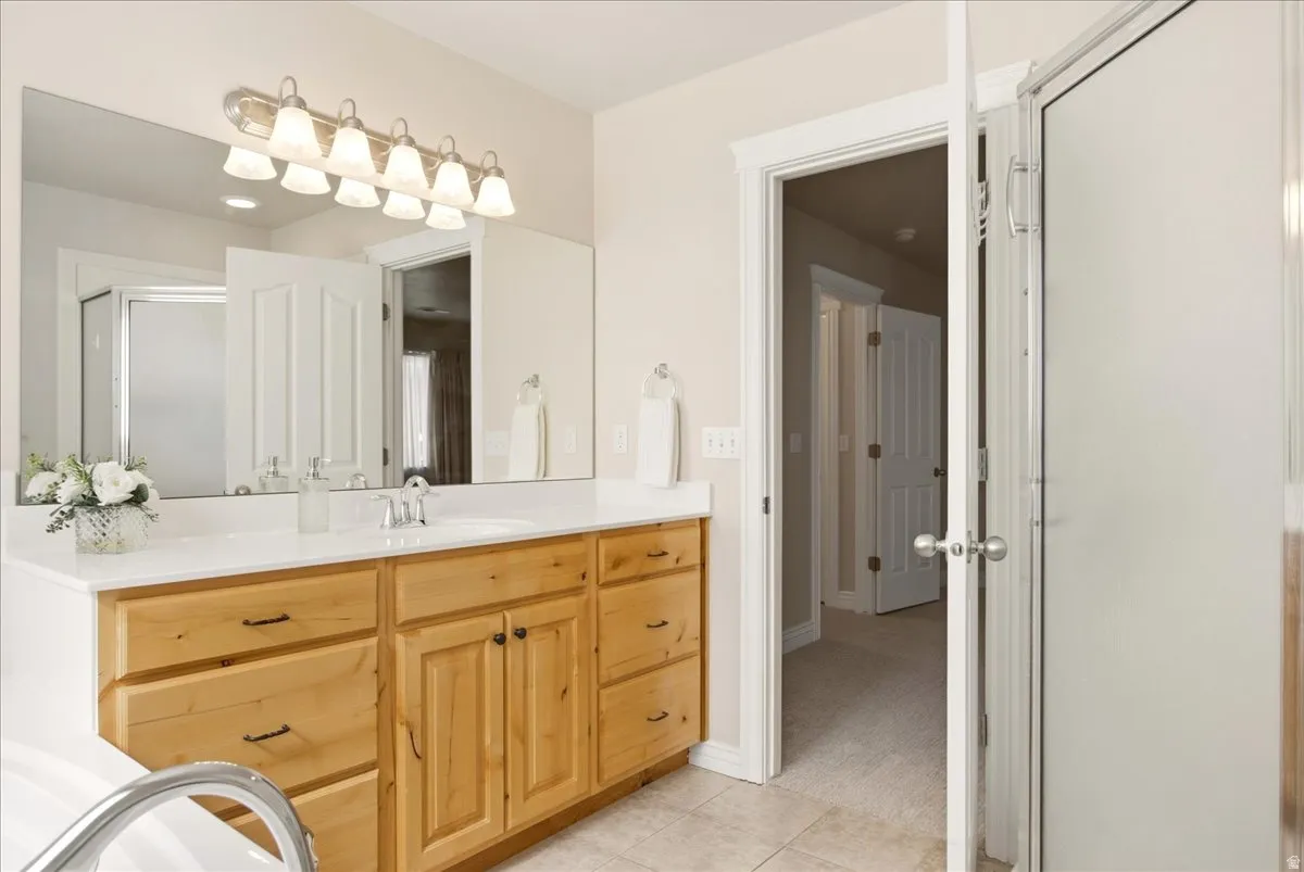 Primary bathroom vanity with a white countertop and wood-finish cabinetry