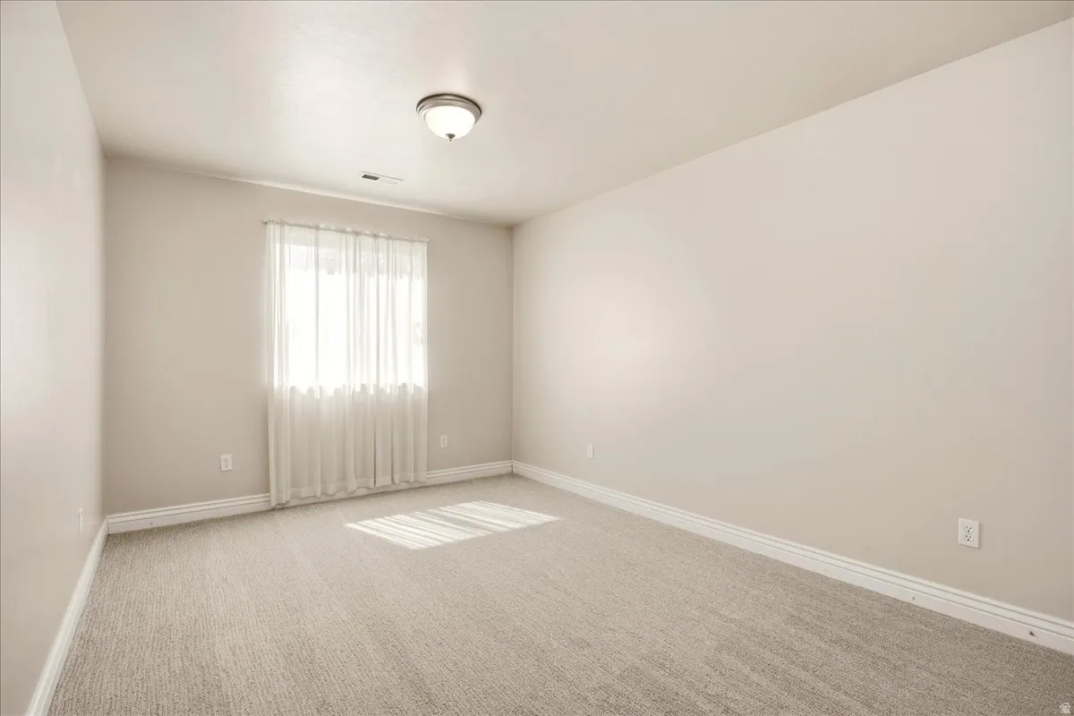 Carpeted room featuring neutral wall tones, a single window, and a ceiling-mounted light fixture