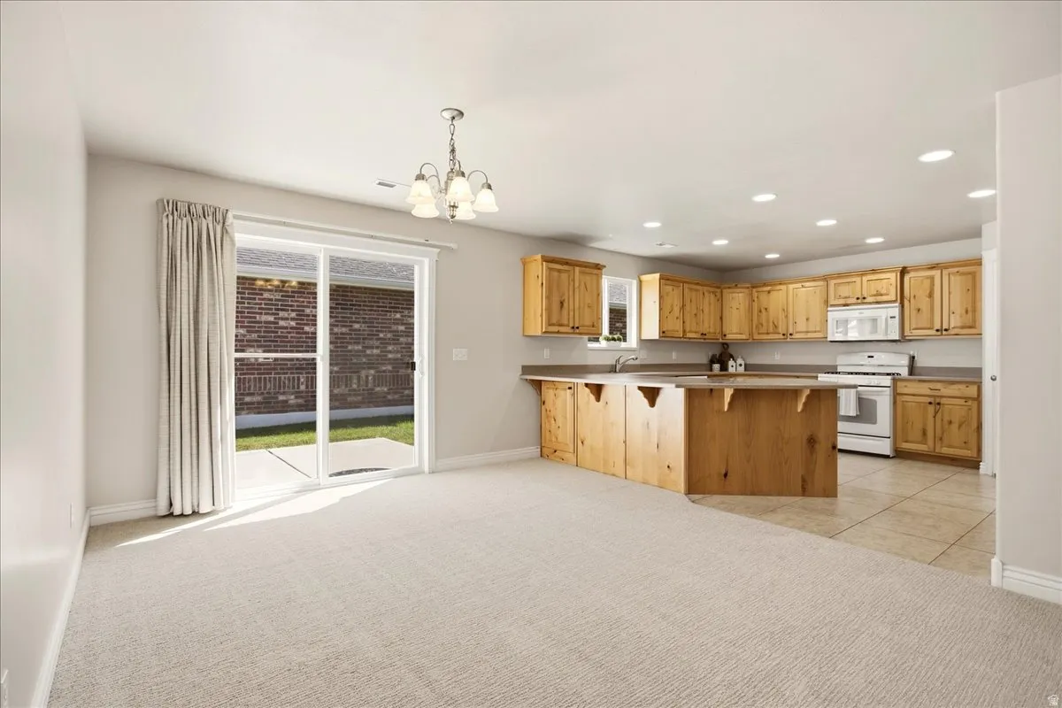 Kitchen featuring wood cabinetry, white appliances, and a central island with bar seating