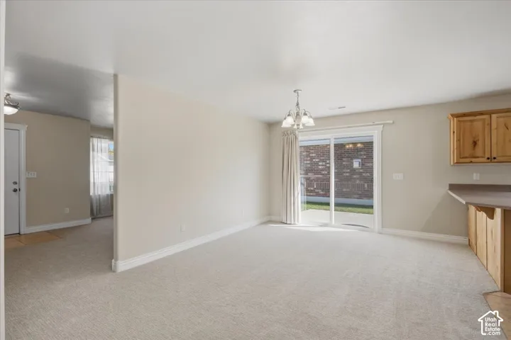 Carpeted living area with a sliding glass door, overhead chandelier, light wood cabinetry