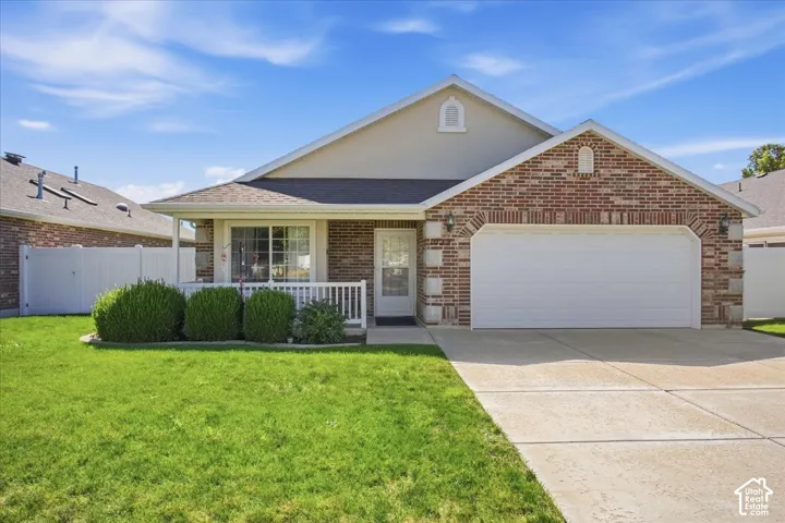 Brick and siding exterior with a covered porch, attached two-car garage, and concrete driveway