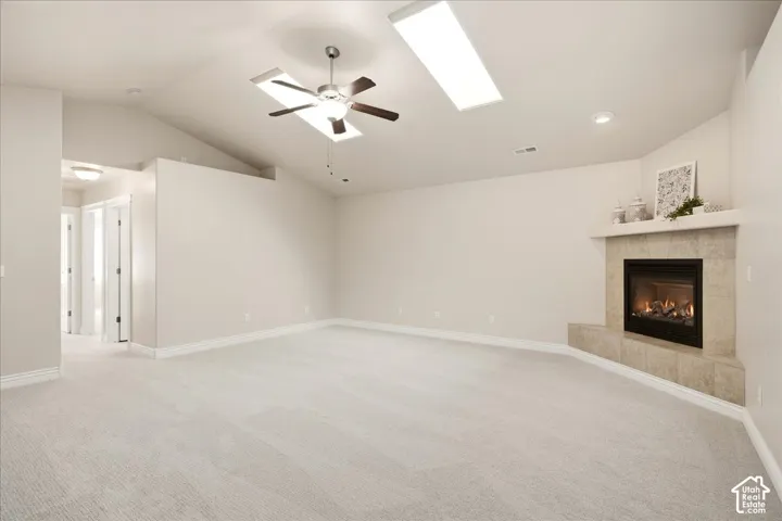 Vaulted ceilings with multiple skylights, recessed lighting, ceiling fan, and a tiled fireplace