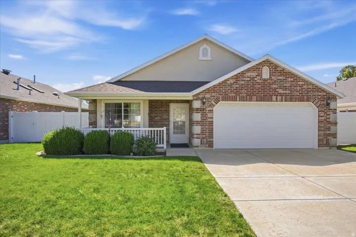 Brick and siding exterior with a covered porch, attached two-car garage, and concrete driveway