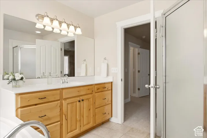 Primary bathroom vanity with a white countertop and wood-finish cabinetry