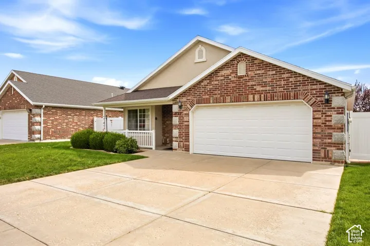 Brick and stucco exterior with an attached two-car garage, concrete driveway, and covered front porch with white railing