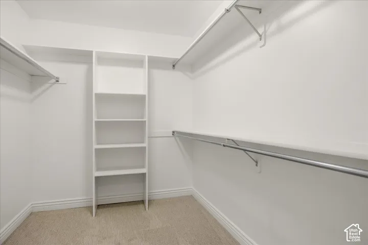 Walk-in closet with built-in shelving, multiple hanging rods, and carpeting
